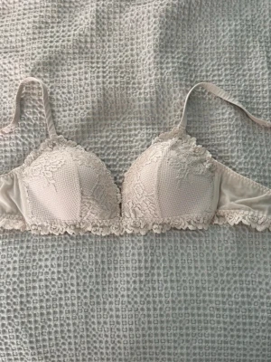 Intimissimi bralette - Söt ljusbeige bh med vadderade kupor och vacker spetsdetalj över hela framsidan. Bh:n har justerbara axelband och spetskant nedtill för en extra feminin touch. Perfekt för dig som gillar romantiska underkläder.