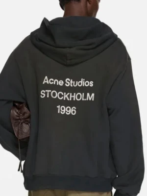 Svart hoodie från Acne Studios - Cool svart hoodie från Acne Studios med tryck på ryggen: 'Acne Studios STOCKHOLM 1996'. Klassisk design med huva och ribbade muddar. Perfekt för dig som gillar streetwear och enkel stil. Materialet är mjukt och bekvämt, troligen bomull.