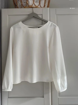 Vit långärmad blus med rund hals -  Härlig sommarblus från Jascha med rund hals och långa ärmar i mjukt material. Mycket fint skick, endast använd några få gånger.  Djur och rökfritt hem.  Besök gärna mina andra annonser.