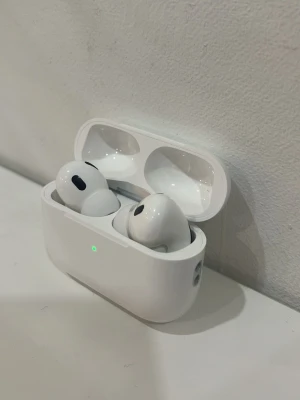 Hörlurar med laddningsetui - Säljer ett par vita hörlurar  med tillhörande laddningsetui. De är trådlösa in-ear hörlurar med stilren design och blank finish. Perfekt för dig som vill ha bra ljud och smidig användning. Etuiet har LED-indikator på framsidan.