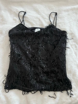 Svart glittrig linnetopp från Vila - Svart glittrig linnetopp från Vila med tunna axelband och paljetter som hänger