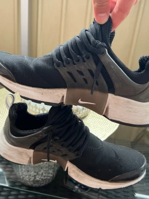 Nike air Max presto - Säljer ett par svarta Nike Presto sneakers med mesh-ovandel och plastdetaljer vid snörningen. Skorna har en vit och svart sula samt Nike-logga på sidan. Lågt skaft och bekväm passform, perfekta för en sportig och avslappnad stil. Köpte de från Nike länge sen och har inte ens använt dom i länge för dom passade inte mig. Dom finns inte längre på Nike.