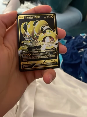 Regigigas GX Pokémonkort svart/guld - Säljer ett Regigigas GX Pokémonkort i svart och guld med holografiska detaljer. Kortet har en cool design med Regigigas i fokus och tydliga attacker och stats. Perfekt för samlare eller Pokémonfans!