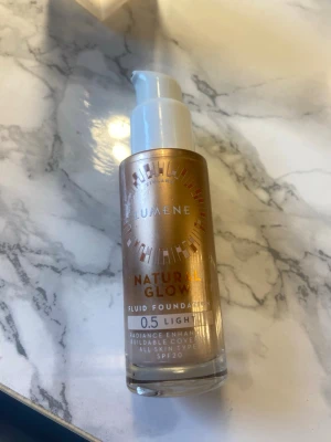 Lumene Natural Glow Foundation 0.5 Light - Lumene Natural Glow Fluid Foundation i nyansen 0.5 Light ger en naturlig lyster och har SPF 20. Kommer i en glasflaska med pump och guldiga detaljer. Passar alla hudtyper och har en lätt, flytande formula som går att bygga upp för mer täckning.