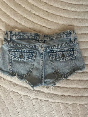 Blå jeansshorts från Pull&Bear - Säljer ett par blå jeansshorts från Pull&Bear med slitna detaljer. Shortsen har fickor där bak.  