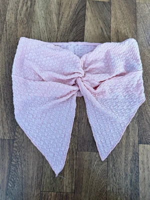 Tubtopp med knyt 3 pack - Tubtopp med knyt framtill och spetsiga kanter, 3 pack i färgarena rosa, svart och vit. Toppen har en strukturerad, våfflad yta och är axelbandslös. Perfekt för sommaren och ger en söt och unik look till din outfit. Endast testade.