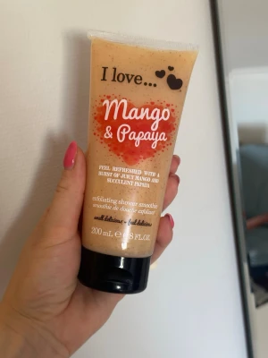 I Love... Mango & Papaya duschkräm - Exfolierande duschkräm från I Love... med doft av mango och papaya. Innehåller 200 ml och kommer i en mjuk plasttub med svart lock. Krämens färg är ljusorange med små exfolierande korn för en fräsch känsla i duschen.