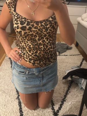 Leopardmönstrad topp med kort ärm - Säljer en leopardmönstrad topp med korta ärmar och rundad urringning. Toppen är figurnära och har en snygg, trendig look som passar perfekt till jeans eller kjol. Materialet känns mjukt och stretchigt, vilket gör den bekväm att bära.