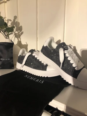 Gråa sneakers från Numeris - Snygga sneakers från Numeris i grått filtmaterial med vita detaljer och grov vit sula. Skorna har vita skosnören och låg profil. Perfekta för dig som gillar en stilren och modern look.