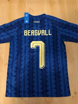 Bergvall #7 – Sverige Borta (storlek M) - Bergvall #7-tryck. Sverige Borta (blå). Storlek M. Helt ny och aldrig använd. Skickas snabbt 🚚💨  Mått (M): Halvt bröstmått 53 cm • Längd 74 cm • Ärmbredd 23 cm • Axelbredd 44 cm • Ärmlängd 40 cm • Manschett 19 cm.  🔥 Fan Edition – normal och bekväm passform. 🇸🇪 Sverige landslag.  📩 Frågor eller prisförslag? 🛍 Bundle-rabatt upp till 20% 💰 📦 Skickas samma eller nästa dag