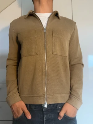 Beige overshirt från Selected Homme - Beige overshirt från Selected Homme tillverkad i bomull, polyamid och elestan. Strl S. Inga defekter. Modellen är 178 cm och väger 77 kg. Hör gärna av dig vid frågor!