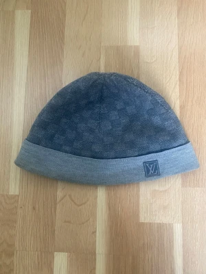 (Äkta) Blå Mössa från Louis Vuitton - Riktigt snygg Louis Vuitton Petit Damier mössa i blå. Denna ger din outfit den där sista touchen. Självklart äkta.