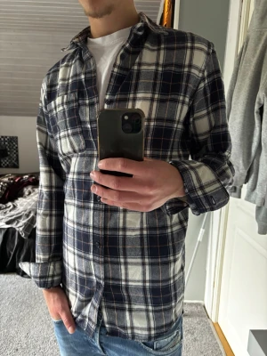 Blårutig skjorta - Snygg blårutig skjorta med vita och mörkblå rutor. Skjortan har långa ärmar, klassisk krage och knäppning framtill. Perfekt till jeans för en avslappnad look.