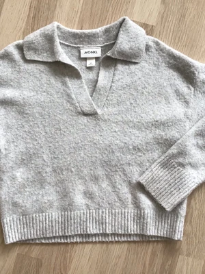 Ljusgrå stickad tröja från Monki, storlek XS - Mysig ljusgrå stickad tröja från Monki med krage och v-ringning. Tröjan har långa ärmar och breda ribbade muddar vid ärmslut och nederkant. En välanvänd favvotröja, så har en del noppror, men i övrigt bra skick, hel och ren. Just nu fri frakt, så du betalar bara för tröjan. Jag har fler plagg ute, och hittar du något mer från min garderobsutrensning, så skickar jag allt i samma paket.