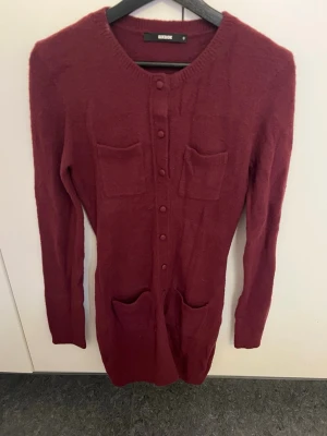 Vinröd klänning från Bik Bok - Vinröd stickad klänning från Bik Bok med rund halsringning, knappar framtill och fyra fickor. Utan prislapp men aldrig använd
