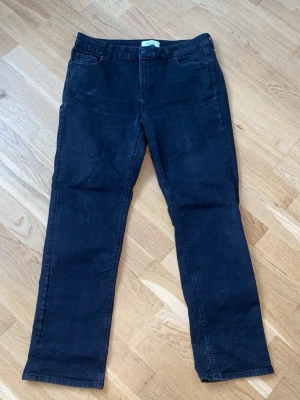Mörkblå raka jeans - Säljer ett par mörkblå jeans med rak passform och klassisk femficksdesign. Jeansen har bälteshällor och knappgylf. Materialet är denim i bomull och de har en enkel, stilren look utan slitningar eller dekorationer.
