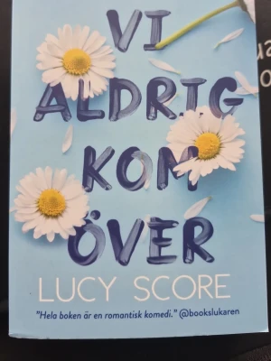 Vi aldrig kom över av Lucy Score - En romantisk komediroman av Lucy Score med blått omslag dekorerat med prästkragar. Boken handlar om Naomi som flyttar till småstaden Knockemout i Virginia och möter både kärlek och utmaningar. Perfekt för dig som gillar känslor, humor och spänning. Aldrig läst heöt nyköpt. Anledning till säljning är för aty den är på svenska. Nypris 199kr