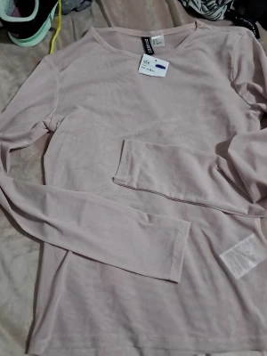 Ljusrosa långärmad genomskilning topp från divided - En enkel och stilren ljusrosa långärmad topp från divided. Passformen är normal och materialet känns lätt och bekvämt. Genomskilning