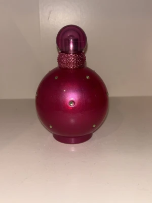 Fantasy parfym från Britney Spears - Säljer en ikonisk parfym från Britney Spears, Fantasy. Flaskan är rund och metallic rosa med små kristalldekorationer och ett glittrigt band runt halsen. Perfekt för dig som gillar söta och fruktiga dofter. Se bild på hur mycket de är i.
