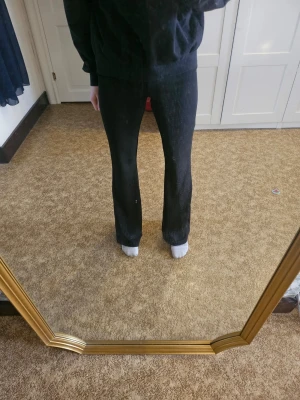 Svarta utsvängda byxor - Säljer ett par svarta byxor från gina tricot med utsvängda ben och hög midja som går vika ned till önskad längd. De är gjorda i ett mjukt och stretchigt material som sitter skönt och följer kroppen. Perfekt för dig som gillar en trendig och bekväm stil.