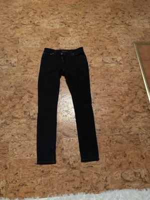 Nudie jeans - Snygga svarta jeans och klassisk femficksdesign. Jeansen har smal passform och dragkedja med knapp framtill. Perfekta för en trendig och stilren look.
