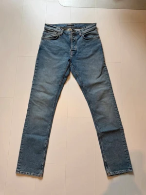 Nudie Grim Tim - Klassiska blå jeans från nudie jeans med slim rak passform. Jeansen har en tidlös tvätt och är tillverkade i slitstark denim. Perfekta för dig som gillar en enkel och clean stil. Storlek 32/32! Har du frågor om mått eller annat så tveka inte på att skriva! 