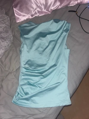 Ljusblå/turkos oneshoulder topp från h&m - Säljer en ljusblå/turkos oneshoulder topp från Divided by H&M. Toppen är ärmlös och har en tight passform med mjukt, stretchigt material. Den är i storlek S men passar även mindre eller större då den är stretchig. Knappt använd. 