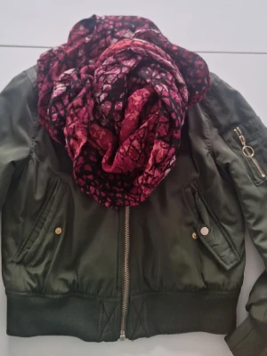 Vinröd mönstrad sjal - Säljer en vinröd sjal med unikt mönster i olika nyanser av rött och svart. Sjalen är rektangulär och har ett lätt, luftigt tyg som gör den enkel att styla. Perfekt accessoar för att lyfta din outfit med lite färg och mönster. Tubform ca 105x65 cm