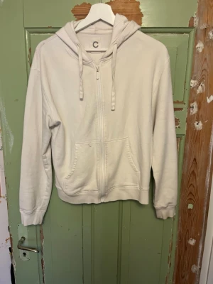 Vit zip hoodie med fickor - Snygg vit hoodie med dragkedja framtill och två stora fickor. Tröjan har använts men är i bra skick. Storlek S. Priset kan alltid diskuteras, hör av er om ni vill ha fler bilder!