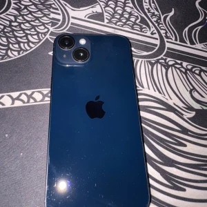 iPhone 14 - Snygg blå iPhone 14 med dubbla kameror och 128GB lagring. Batterihälsa på 84%. Mindre repor och normalt slitage syns på både fram- och baksida, men inget som påverkar funktionen. Perfekt för dig som vill ha en kraftfull och pålitlig mobil till ett bra pris.