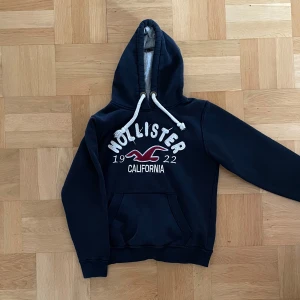 Mörkblå Hollister hoodie  - Säljer en snygg Hollister hoodie i storlek small. Hoodie skulle jag säga sitter som S. Hoodien är perfekt nu till hösten! Ställ frågor vid minst funderingar. Priset är ej hugget i sten!!