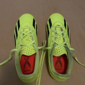 Adidas Crazyfast gula fotbollsskor - Säljer ett par Adidas Crazyfast fotbollsskor i neon-gult med svarta ränder och detaljer. Skorna har snörning, platt sula med dobbar i rött och vitt, samt ventilerande hål på ovansidan. Perfekt för dig som vill sticka ut på planen och ha grymt grepp.