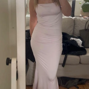 Ljusrosa långklänning med smala axelband - Supersnygg långklänning i ljusrosa med smala axelband och figurnära passform. Klänningen har en enkel och stilren design som framhäver siluetten. Perfekt för dig som vill ha en elegant look med minimalistisk vibe.