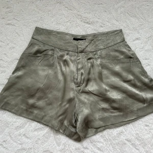  Gröna satinshorts från Gina Tricot XS - Snygga gröna shorts från Gina Tricot i storlek XS. De har en hög midja, sidfickor och stängs med dragkedja och knapp framtill. Materialet är i satin och känns lyxigt. Skriv om flera bilder önskas 🥰