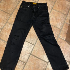 Armani Jeans Blues Factory - Svarta jeans från Armani Jeans Blues Factory med klassisk femficksdesign och silverfärgad logga på bakfickan. Jeansen har rak passform