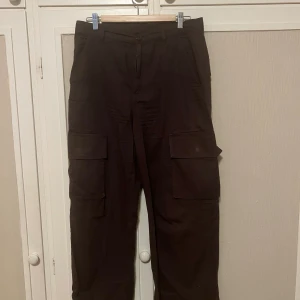 Bruna cargopants  - Säljer ett par bruna cargopants från Monki i storlek 40. Byxorna har flera stora fickor på sidorna och bak, rak passform, super praktiska och sköna på! Använda en par gånger men i bra skick!