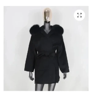 Svart kappa med fuskpäls och bälte - PRIS KAN DISKUTERAS VID SNABBT KÖPStilren svart kappa med breda slag och stora fuskpälsdetaljer på axlarna. Jackan har omlottknäppning och knyts i midjan med ett matchande bälte. Långärmad och med en rak, något oversized passform. Perfekt för dig som vill ha en elegant look med edge.