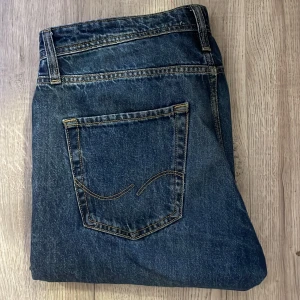 Blå jeans - Mörkblåa fräscha jeans från Jack and Jones. Perfekt för dig som vill se riktigt fräsch och stilig ut. Skick 8,5/10. W31 L30. Skriv vid minsta fråga eller fundering. Pris kan självklart diskuteras vid snabb affär.