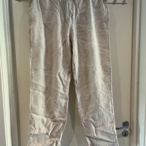Beiga linnebyxor från H&M XL - Snygga och luftiga beiga linnebyxor från H&M i regular fit. Byxorna har resår i midjan och raka ben, perfekta för en chill och avslappnad stil. Tillverkade i linne för en skön känsla och somrig vibe.
