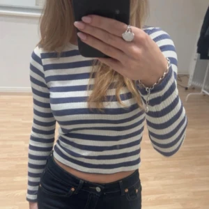 Randig topp - Söt croppad långärmad topp med blå och vita ränder. Toppen är ribbad och har en tight passform, perfekt till exempel till höga jeans. Står storlek 146/152 men är som en xs. Endast använd 2 gånger💙