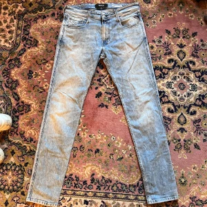 Replay Anbass ljusblå slim jeans 32/32 - Säljer ett par Replay Anbass jeans i ljusblå tvätt med slim fit. Klassisk femficksmodell, snygga slitningar och detaljer vid fickorna. Jeansen har normal midja och raka ben, perfekta för en chill och stilren look. Midja 42cm längd 103cm (29)