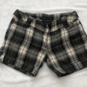 Rutig ullshorts från Amisu - Snygga rutig shorts från Amisu i svart, grått och vitt. Gjorda i mjuk ullmix med klassiskt rutmönster och knappdetalj på benen. Perfekta för dig som vill ha en trendig och bekväm look.