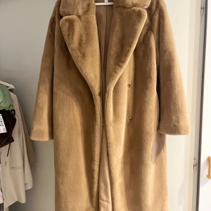 Beige pälsjacka från H&M XS - Säljer en beige pälsjacka från H&M i storlek XS. Jackan har en oversized passform, bred krage och stängs med dolda knappar framtill. Mjuk och fluffig känsla, perfekt för kyliga dagar. Fodrad insida för extra komfort.