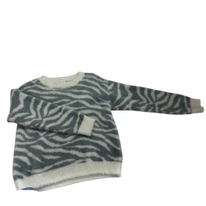 Zebramönstrad stickad tröja Lindex - Supermjuk stickad tröja från Lindex med blå/grå och vitt zebramönster. Rund halsringning, långa ärmar och ribbade muddar. Perfekt för dig som vill sticka ut med ett djurinspirerat print.