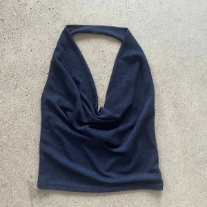 Glittrig marinblå halterneck topp från Subdued - Säljer en blåglittrig festtopp från Subdued med halterneck och öppenrygg i storlek M. Fin passform och i väldigt bra skick.