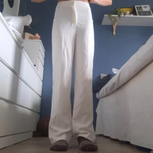 Vita vida kostymbyxor - Snygga vita kostymbyxor med rak och vid passform. Byxorna har klassisk look och är tillverkade i ett lätt tyg som ger en clean och fräsch vibe. Har fläckar mellan benen.