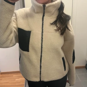 Pilejacka - Mysig vit teddyjacka från Cotton On med svarta detaljer och dragkedjor. Inprincip oanvänd. Sitter bra på mig som är 168 cm, inte för oversized. 