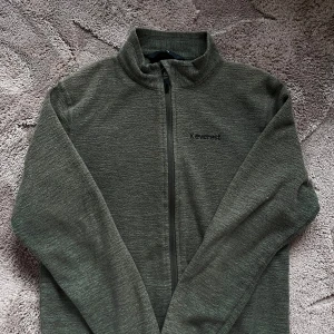 Grå fleecejacka från Everest - Mysig grå fleecejacka från Everest med hel dragkedja framtill och hög krage. Perfekt för kyliga dagar och enkel att slänga på sig. Broderad Everest-logga på bröstet och mjukt material som håller dig varm.