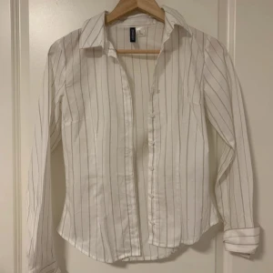 Vit randig skjorta - Vit skjorta med tunna vertikala ränder i grått och knappar framtill