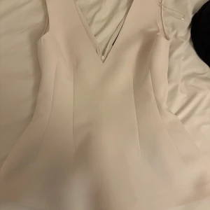 Peplumtopp Zara - Säljer en stilren peplumtopp från Zara. Toppen har en djup v-ringning och är ärmlös, med en lätt utsvängd siluett. Materialet är mjukt och känns lyxigt mot huden, perfekt för dig som gillar minimalistisk design. Endast använd 1 gång!